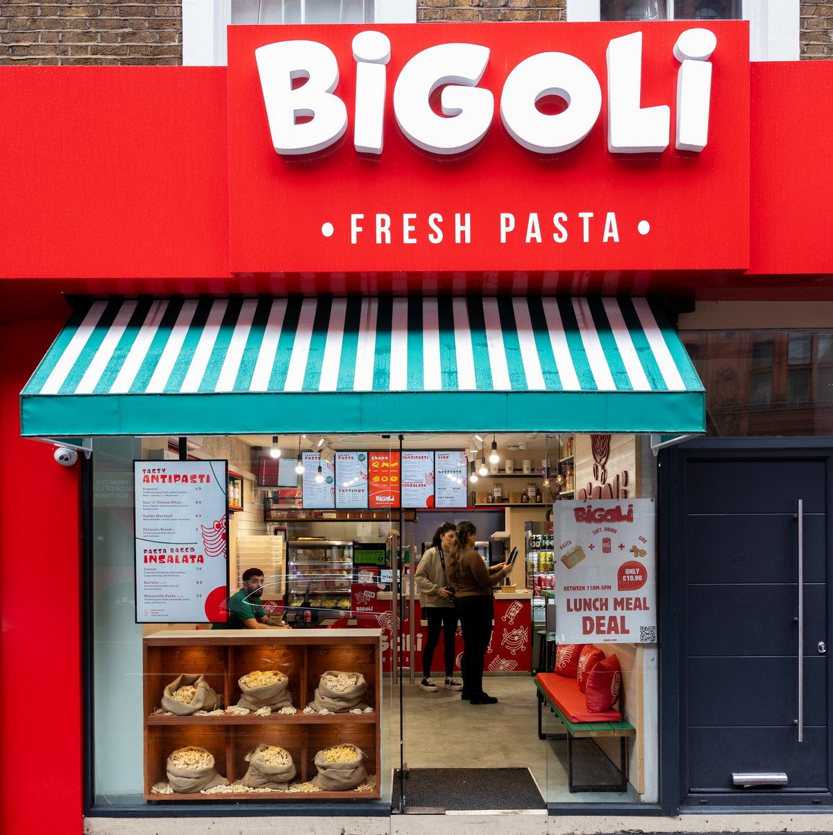 The red Bigoli Fresh Pasta shopfront on City Road with its striped awning and the BIGOLI FRESH PASTA sign, people eating inside the Italian restaurant.