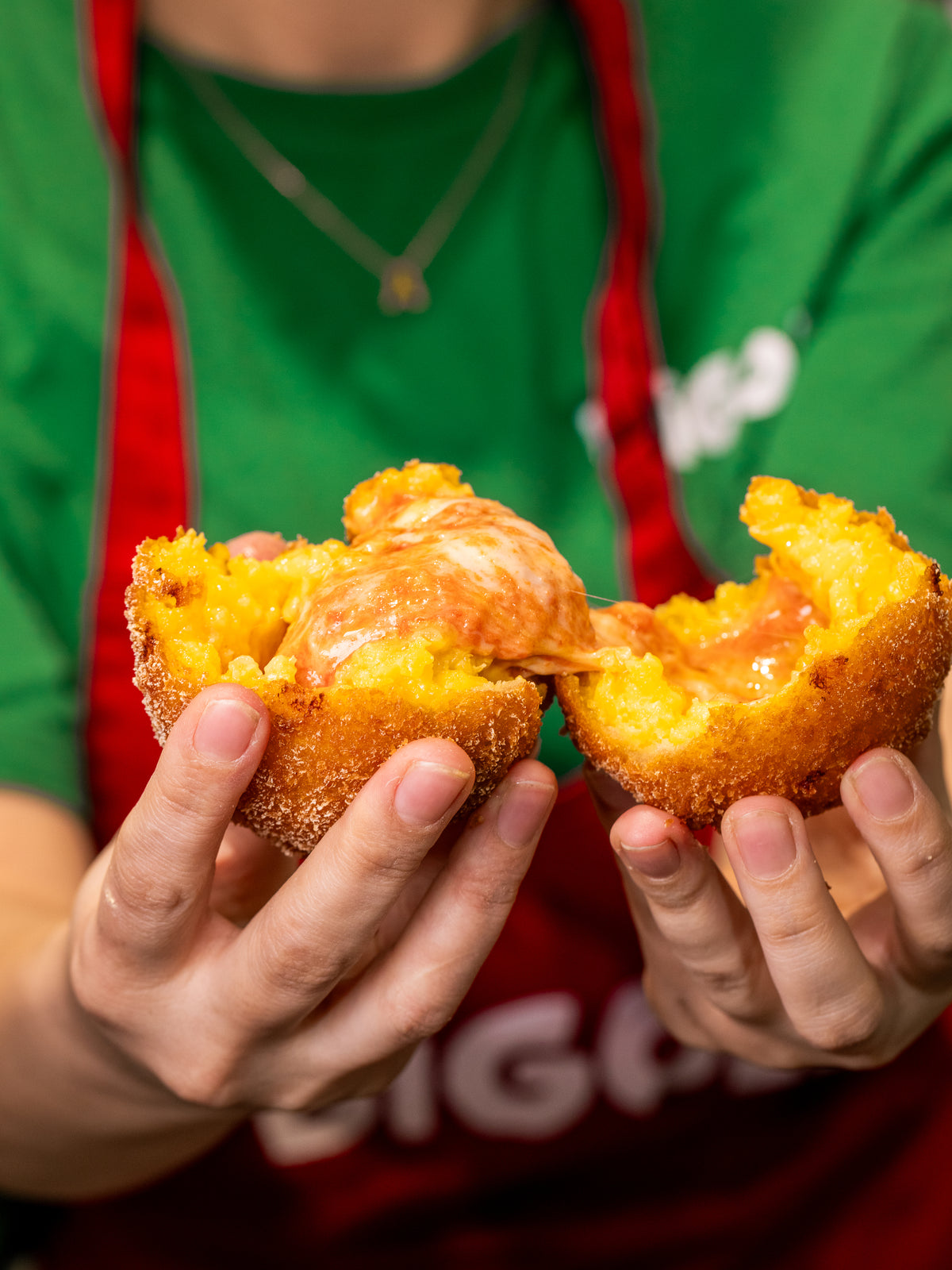 Two hands breaking an arancini open to show the filling, on the counter at Bigoli in Old Street.