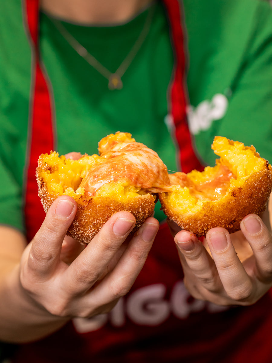 Two hands breaking an arancini open to show the filling, at the Bigoli counter