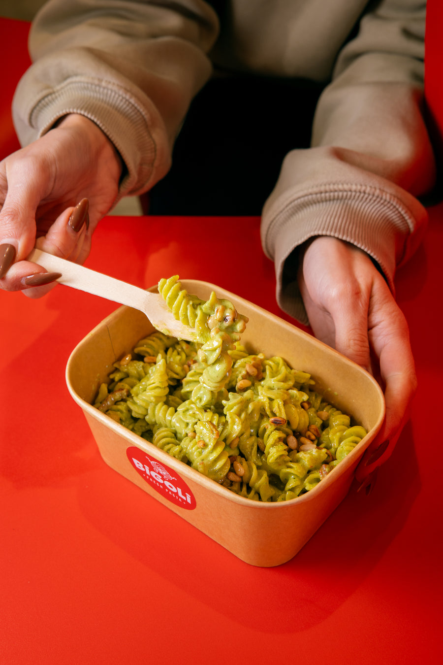 A customer eating fusilli pesto with pine nuts from a Bigoli takeaway box