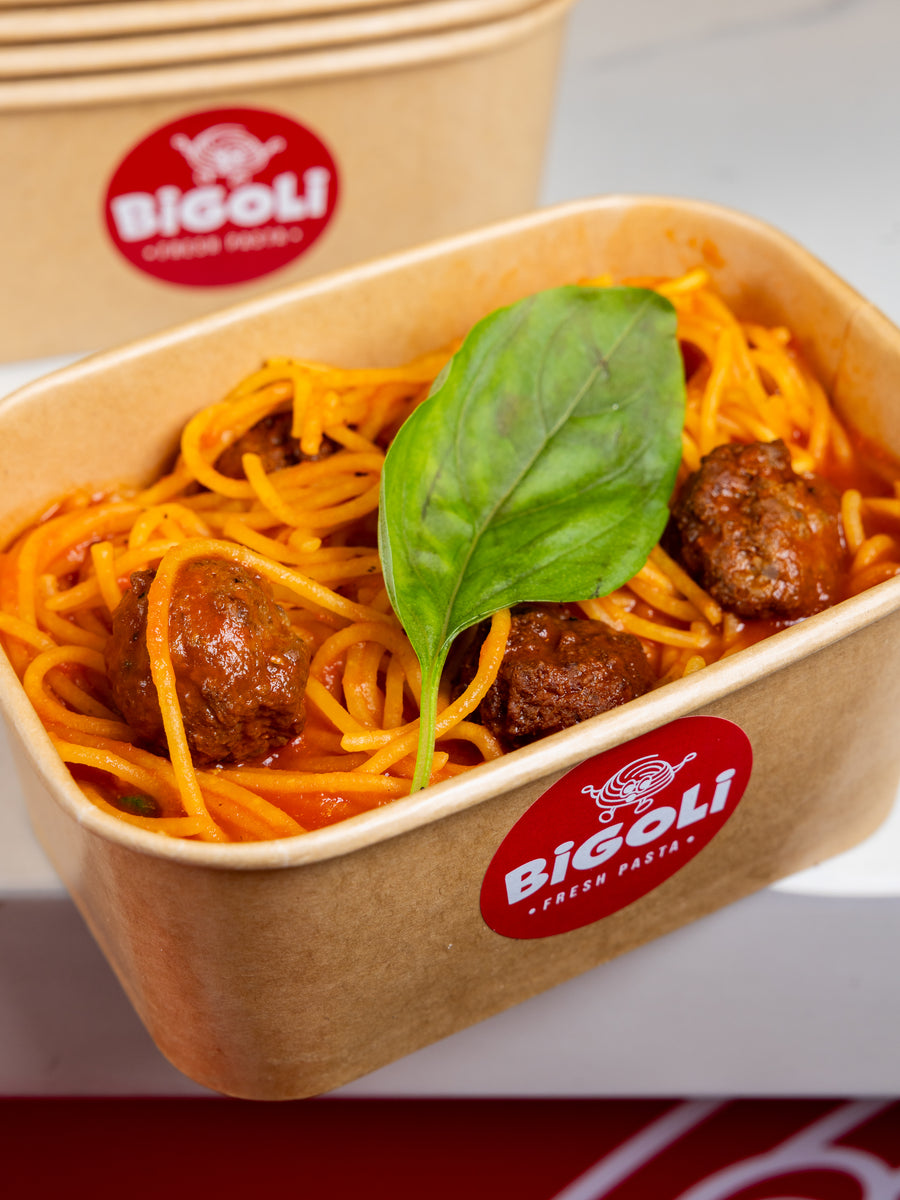 Spaghetti and meatballs in a Bigoli takeaway box with fresh basil