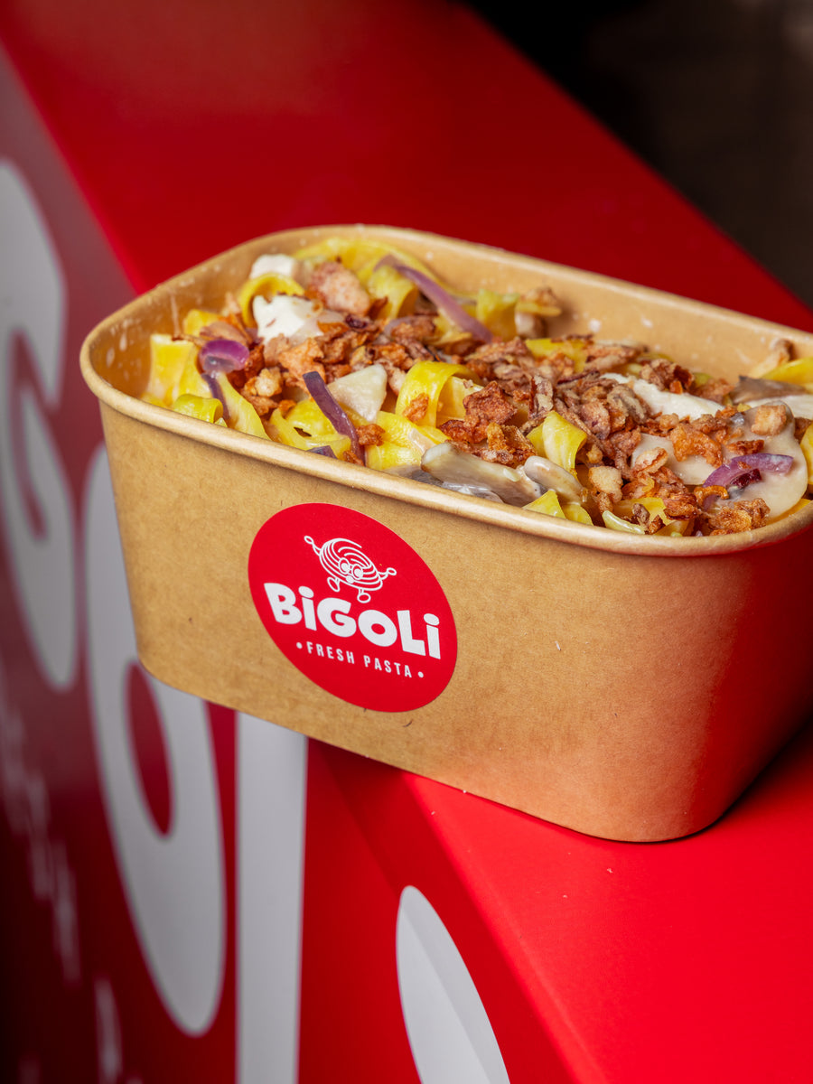 An individual Bigoli box of penne with sausage and red onion, labelled and ready to hand out